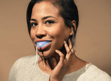 Woman smiling with chin resting on hands.