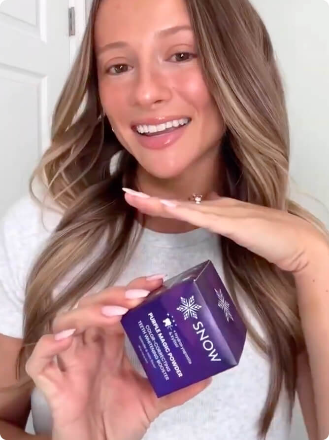Woman holding the SNOW Purple Magic Powder box