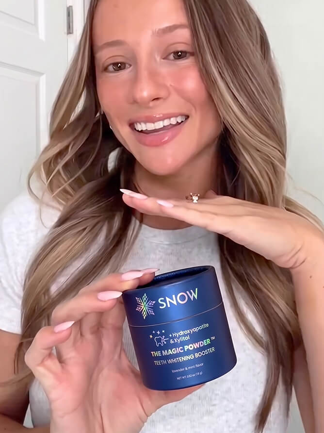 Woman holding the SNOW Purple Magic Powder box