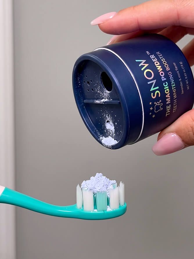 Sprinkling the purple powder onto a toothbrush